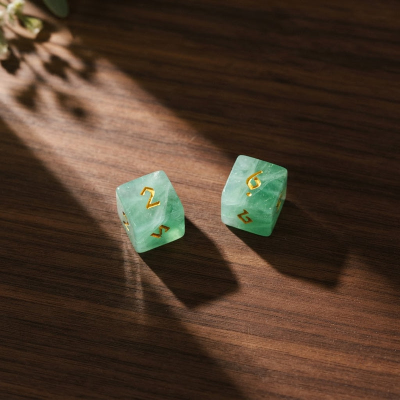 Two green fluorite dice seen from above on a walnut table