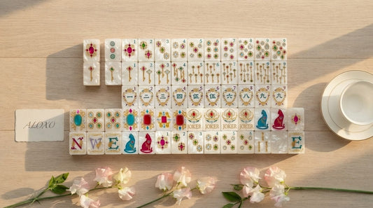 Four women stack a thick mahjong tile on a thinner one at a hotel tournament room table
