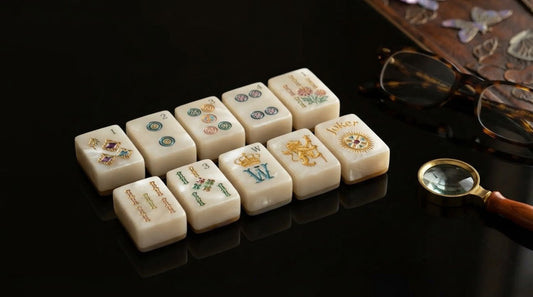 Four women in a sunroom compare the fine detailing on two mahjong tiles across a full table
