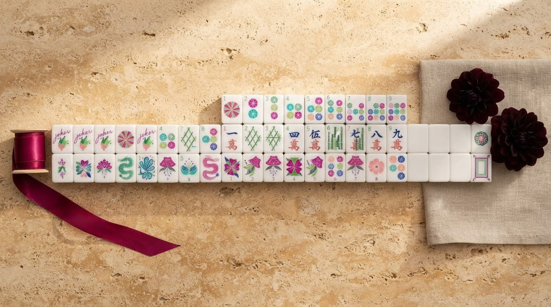 Four women compare a glittering pink mahjong tile with a matte one in a sunlit library room