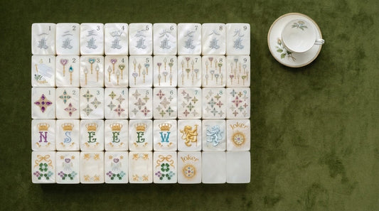 Acrylic and melamine mahjong tiles held up to the light by four women in a fern-filled sunroom