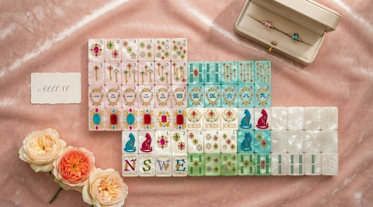 Pastel mahjong tiles set beside a classic bone-and-green set on a bright beach house sunporch