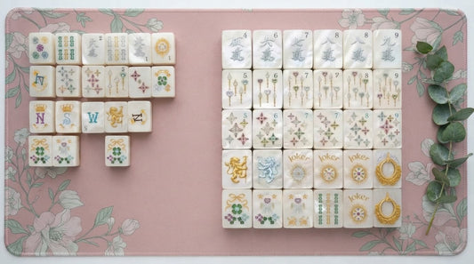 A basic starter mahjong set open beside a polished luxury set at a community center table