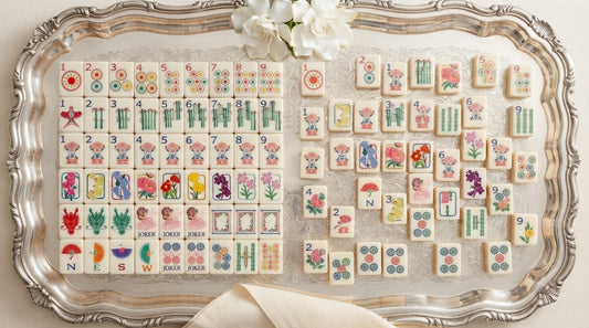 A glossy mahjong tile held beside a matte frosted one on a sunlit rooftop terrace table