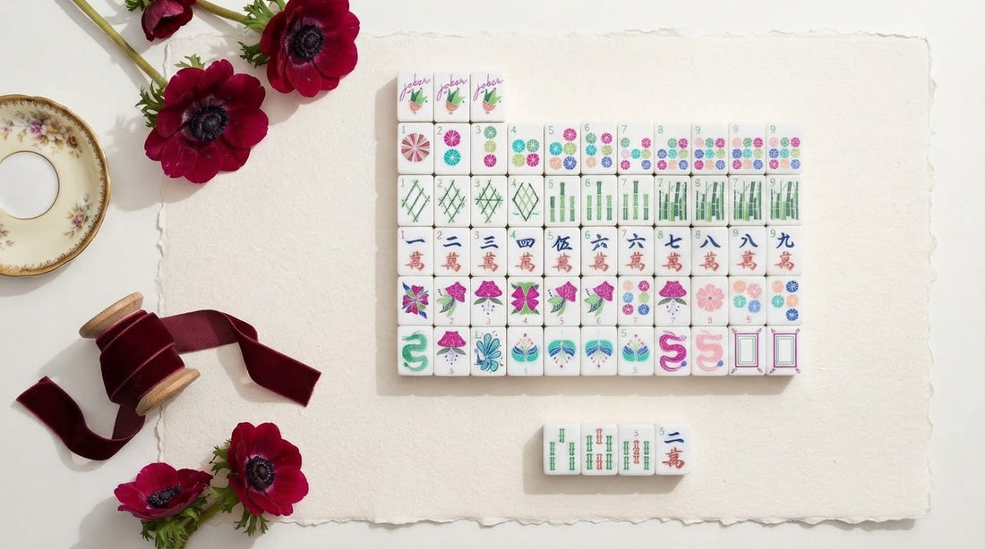 Four women playing mahjong in a bookstore cafe nook with a wrapped gift box on a side table