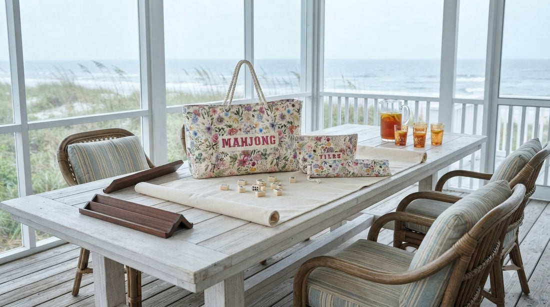 Four women playing mahjong on a breezy beach house sunporch beside an open coastal window