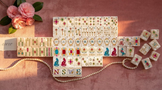 Four women admiring the soft blush tone of their mahjong tiles in a calm spa retreat lounge