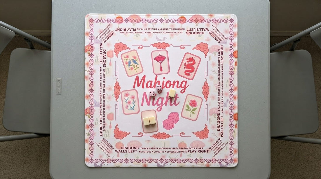 Four women playing a quiet mahjong round on a thick non-slip mat in a book-lined library room