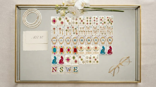 Four women admiring a designer mahjong set's ivory tiles at a sunlit retirement lounge table