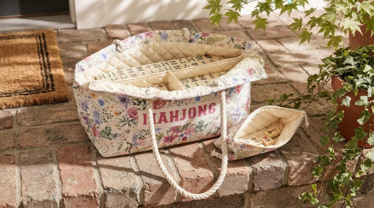 Four women at a marina clubhouse table with a padded canvas mahjong travel bag propped open