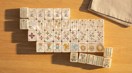 Four women examining the deep engraving on a set of ivory mahjong tiles in a sunlit lounge