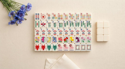 Four women at a senior center game room table counting out a full spread of mahjong tiles