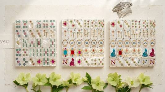 Four women in a hotel tournament room comparing two different mahjong tile materials side by side