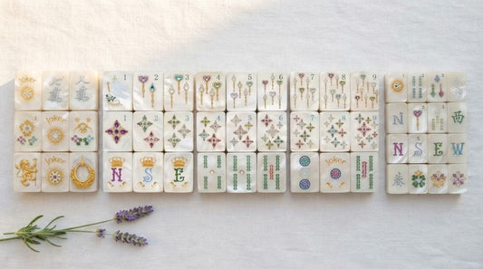 Four women at a library table guiding a newer player through her first hand of mahjong