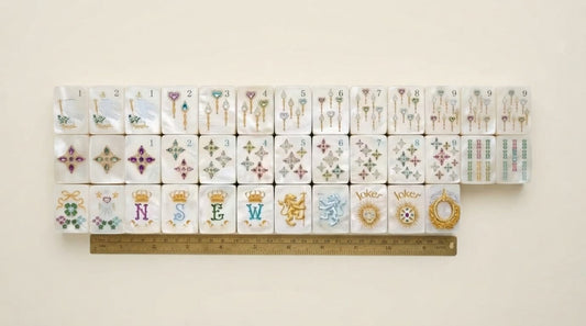 Four women in a hotel tournament room measuring a mahjong tile with a ruler marked in both units