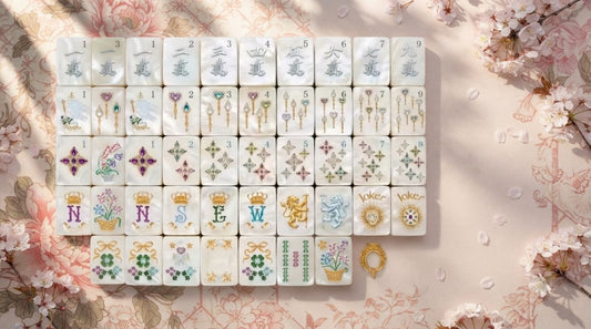 Four women admiring a floral mahjong set on a printed mat in a sunlit plant-filled sunroom