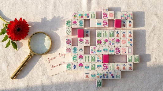 Four women comparing two sets of mahjong tiles by window light in a community center room