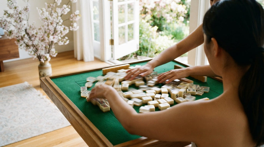 Four women mixing scattered ivory tiles across a mat in a garden conservatory