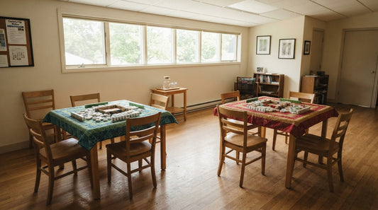Four women laughing around a felt card table at a country club as one rotates to a new seat