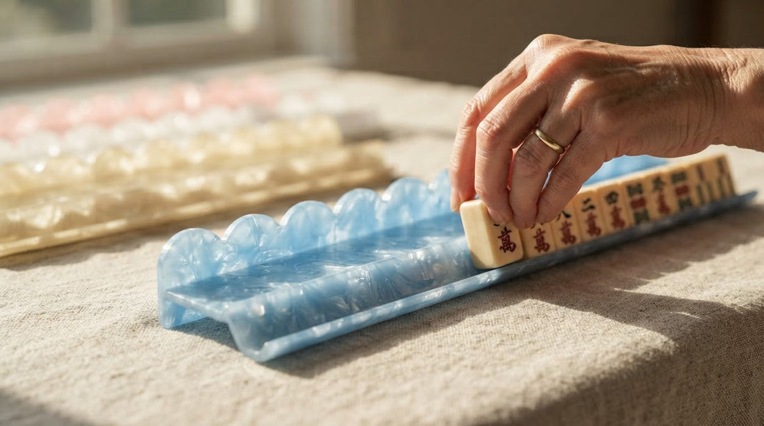 Four women at a fellowship hall table watch as one slides her drawn mahjong tile into the rack.