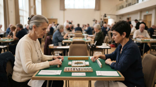 Four women in a hushed mahjong round in a fellowship hall decorated with autumn leaves