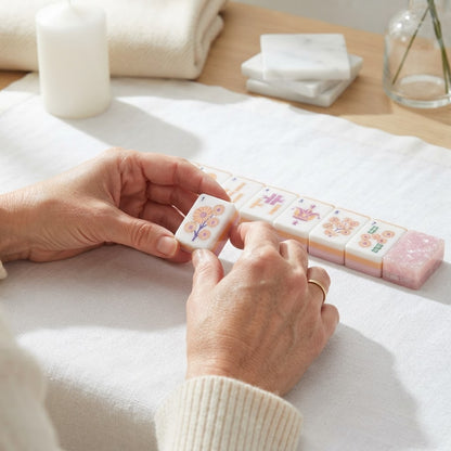 Hands turning over a Blush Garden mahjong tile