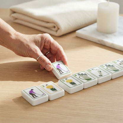 Hand placing a Clubhouse Green mahjong tile on a wood table
