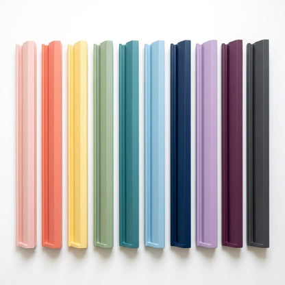 Ten painted wood mahjong racks side by side in ten colors, from blush pink to charcoal