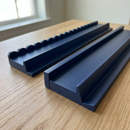 Two navy mahjong racks side by side — one with a scalloped pusher, one with a straight pusher