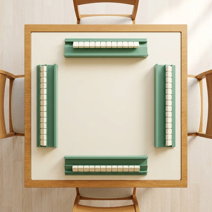 Top view of a square mahjong table with four sage green racks, one on each side, each holding a row of tiles