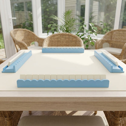 A mahjong table in a sunroom set with four sky blue racks with scalloped pushers