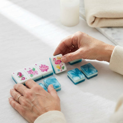 Hands turning over a Flamingo Lagoon mahjong tile