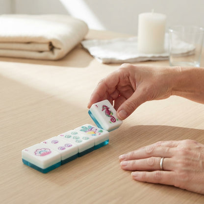 Hand placing a Flamingo Lagoon mahjong tile on a wood table