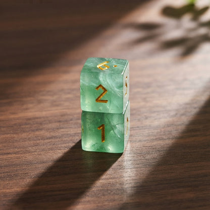 Two green fluorite dice stacked on a walnut table