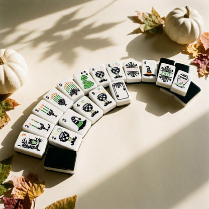Halloween mahjong tiles fanned in an arc among dried autumn leaves