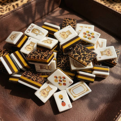 Close-up pile of gold leopard mahjong tiles showing faces, backs and layered edges