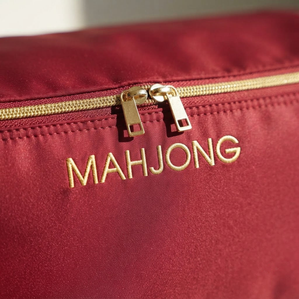 Close-up of gold MAHJONG embroidery and gold-tone zip pulls