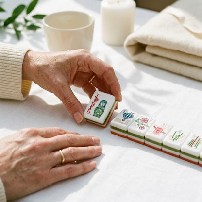 A woman's hands turning a winning tile face-up on white linen