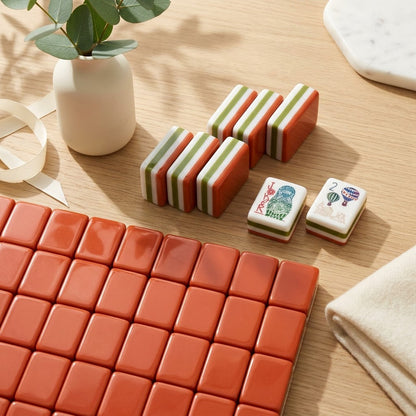 A field of tiles face-down showing the warm terracotta backs, with a few stood on edge to show the layered sides