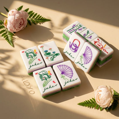 Hand-painted Joker tiles grouped beside peonies and fern
