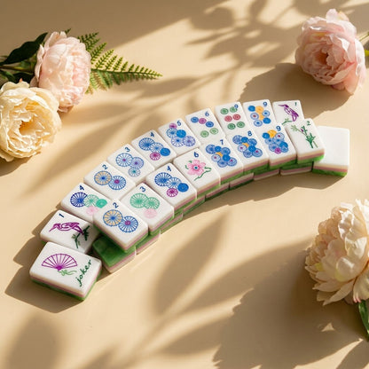 Jade Marble mahjong tiles fanned in an arc beside pale peonies