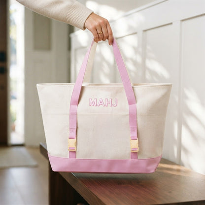 A hand lifting the canvas carryall of the Mahjong Day-Bag Set by its handles