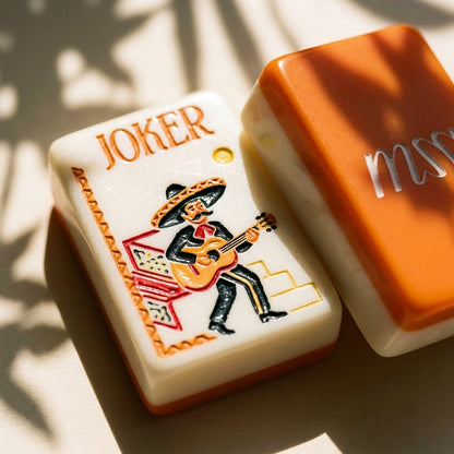 Macro of a mariachi Joker tile beside a tangerine tile back