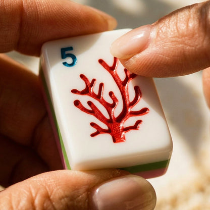 Fingertips holding a red coral dot tile, engraving clearly visible