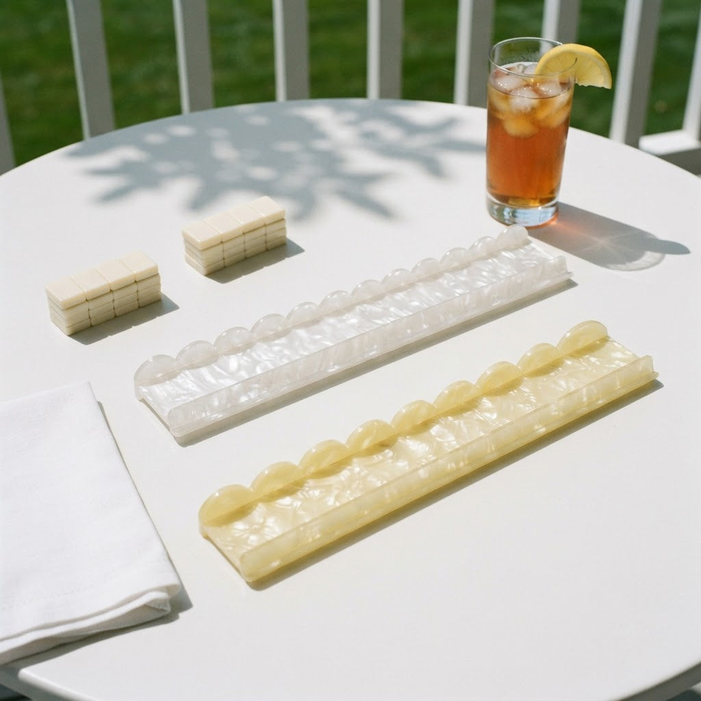 White and yellow Pearl Shell mahjong racks on a porch table with a glass of iced tea