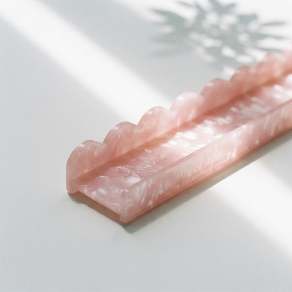 Close-up of the end of a pink Pearl Shell mahjong rack and its scalloped back edge