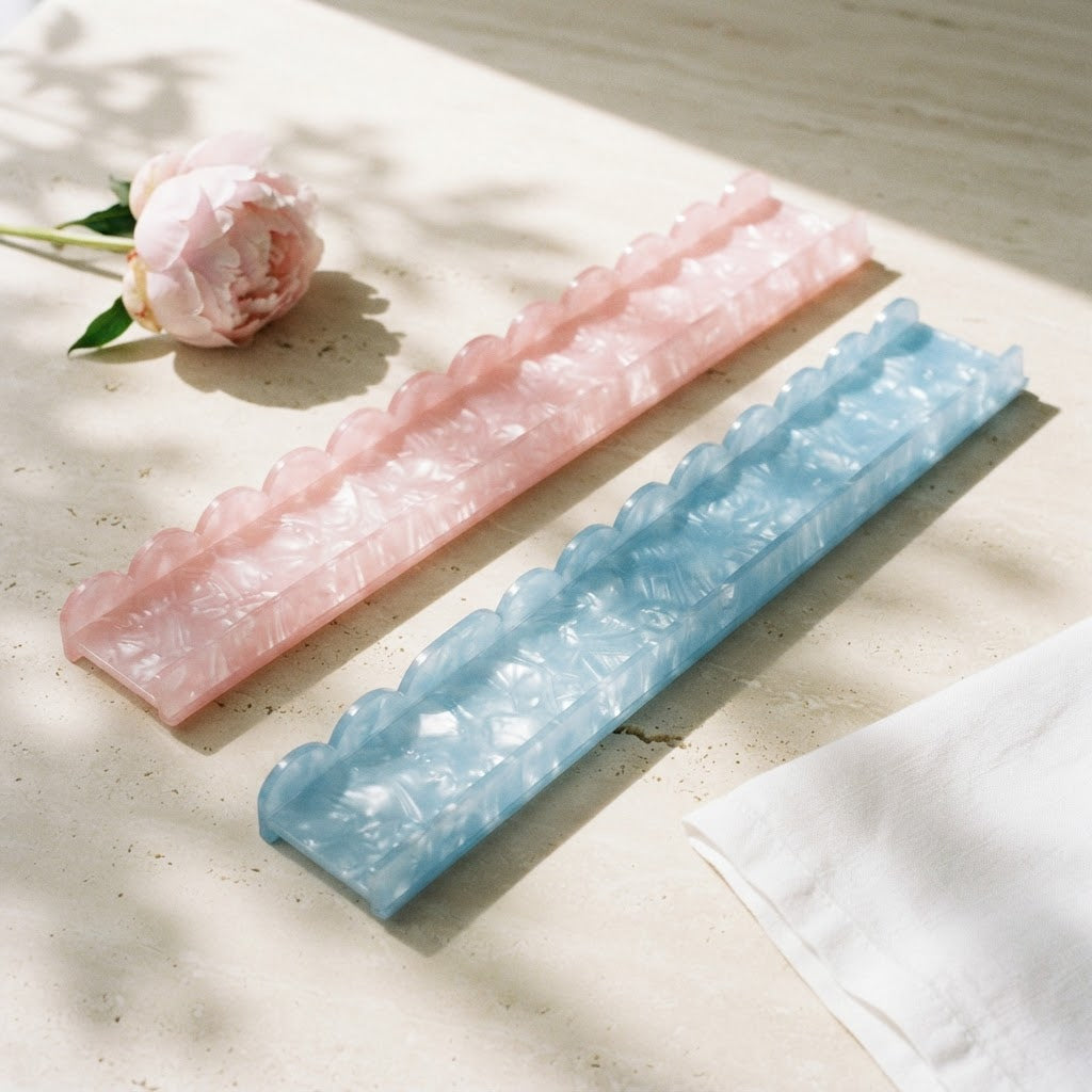 Pink and blue Pearl Shell mahjong racks on a travertine table beside a pale pink peony