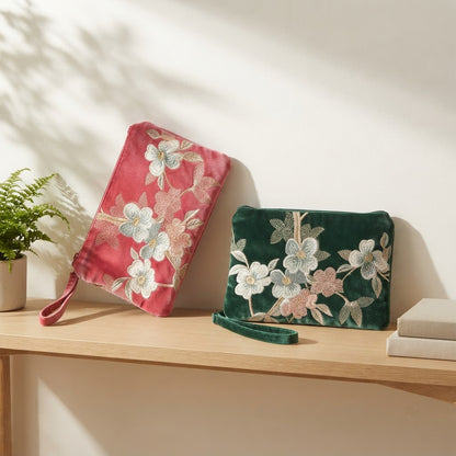 Pink and green embroidered mahjong clutches on a wooden shelf
