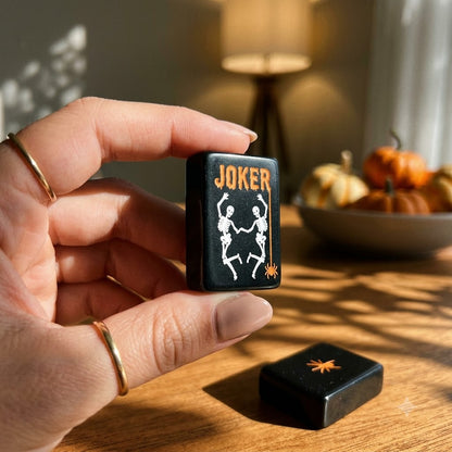 A Joker tile held in a woman's hand