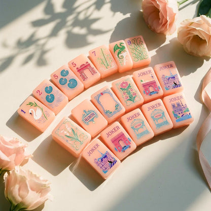Strawberry Paris mahjong tiles fanned in an arc beside pale garden roses